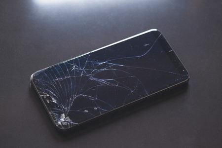 Smartphone with broken touchscreen screen on black table desktopの写真素材