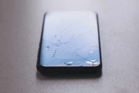 Smartphone with broken screen on black table desktopの写真素材