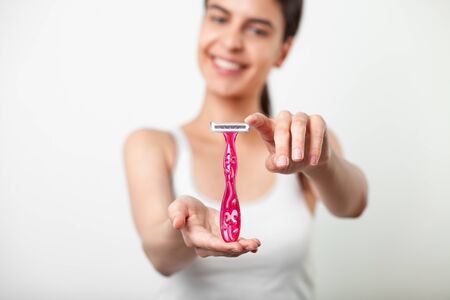 Body care - woman holding pink plastic razor for hair removal between two fingersの写真素材