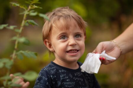 Hygiene - mom wiping the baby face skin with wet wipes. Cleaning wipe, pure, clean, outdoorの写真素材
