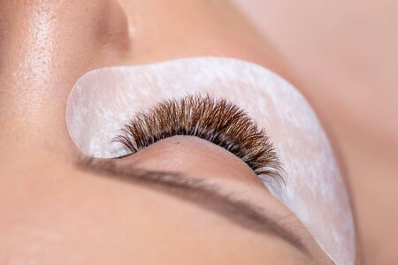 Close up studio shot of a beautiful woman applying cosmetics treatment under eye with hydrogel...