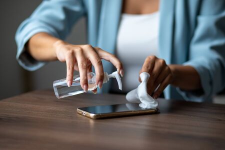 The woman cleans the cell phone with a wet wipe napkin stock photoの写真素材