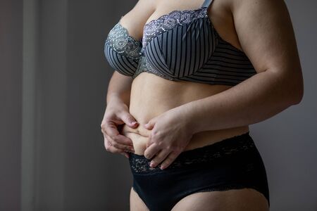 Woman Real Body Plus size Model in lingerie posign and touching fat on stomach, imperfect nonidealの写真素材