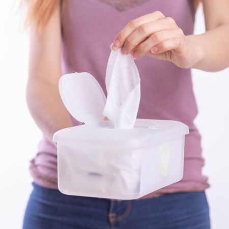 Wet wipes are universal an practical: woman hand take one wipe from big plastic box package for cleaning, home, indoorの写真素材