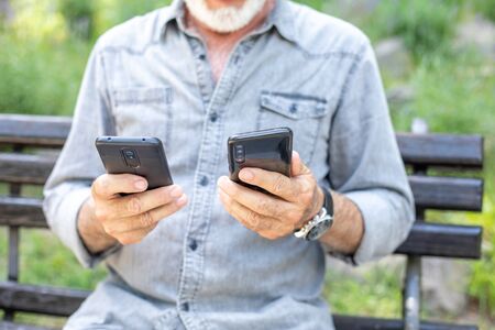 Old man compare two smartphonesの写真素材