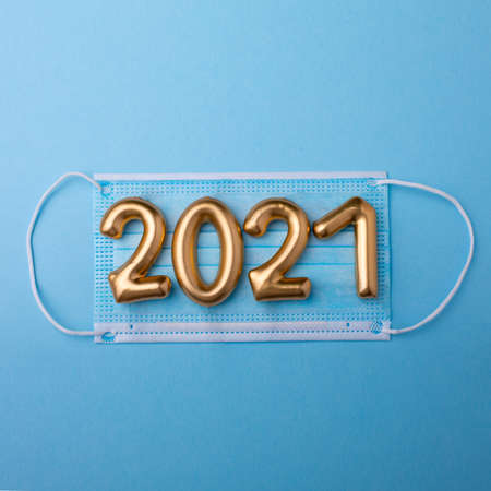 Gold numbers 2021 with face mask on blue background. Happy new pandemic yearの写真素材