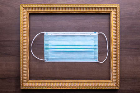 Facemask mask as symbol of prevention coronavirus in gold frame on wooden wall stock photoの写真素材
