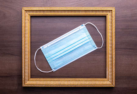 Facemask mask as symbol of prevention coronavirus in gold frame on wooden wall stock photo