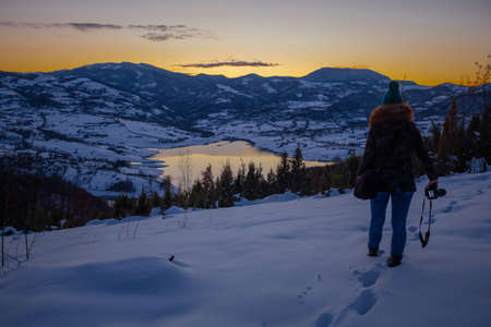 Photographers photographing winter lake mountain scene in sunset, alone in wilderness. Rovni, Valjevo, Serbiaの写真素材