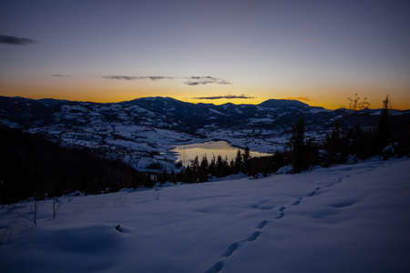 Colorful sunset evening at mountain lake Rovni in snow, beautiful nature winter scene in Serbiaの写真素材
