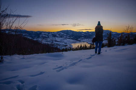 Photographers photographing winter lake mountain scene in sunset, alone in wilderness. Rovni, Valjevo, Serbiaの写真素材
