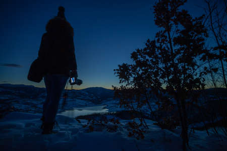 Photographers photographing winter lake mountain scene in sunset, alone in wilderness. Rovni, Valjevo, Serbiaの写真素材