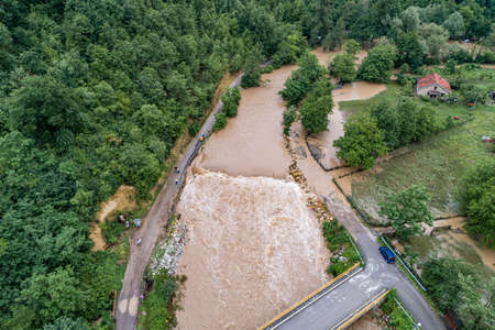 After big rain a river that overflows threatens the road, bridge and property