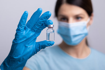 Doctor scientist with protective gloves and face mask holding vaccine medicine dose stock photoの写真素材