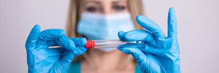 Nurse with facemask holding swab test kit, PPE protective mask and gloves, tube for taking OP NP patient specimen sample, PCR DNA RNA testing protocol process stock photoの写真素材
