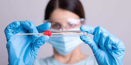 Medical healthcare doctor nurse holding Coronavirus COVID-19 swab test kit, PPE protective mask and gloves, tube for taking OP NP patient specimen sample, PCR DNA RNA protocol process stock photoの写真素材