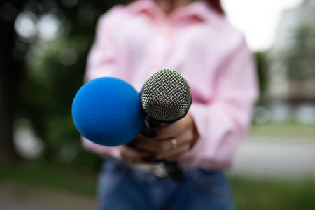 Female journalist at news conference, writing notes, holding microphoneの写真素材