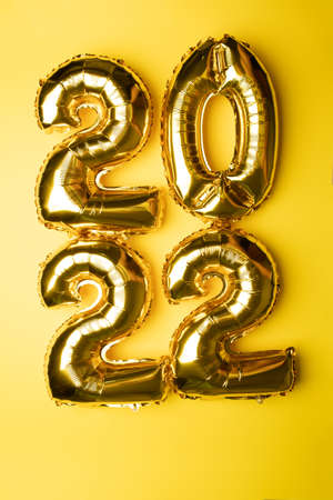2022 Concept New Year from golden foil balloon on yellow background stock photoの写真素材