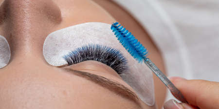 Care of Eyelash Extension with blue brush. Lashes. Woman Eyes with Long Eyelashes in diferent color.の写真素材