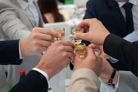 Friends celebrate with rakia brandy at a Serbian wedding. Close up on handsの写真素材