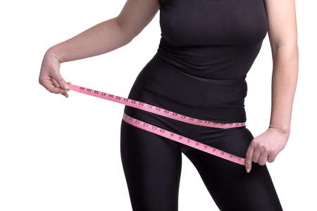 A fat big lady measures the waist measuring tape on a white studio background. happy with the result of the diet and lost a couple of extra pounds. Copy spaceの写真素材