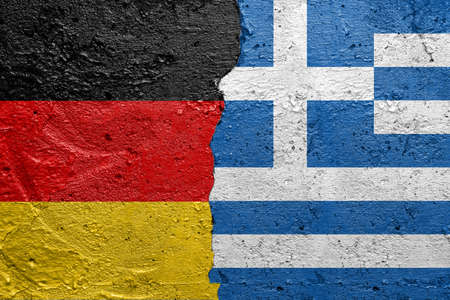 Germany and Greece - Cracked concrete wall painted with a German flag on the left and a Greek flag on the rightの写真素材