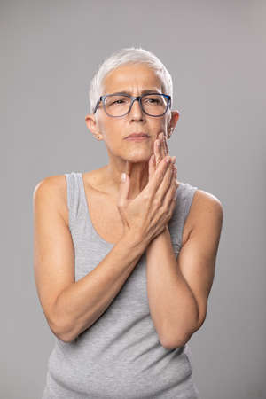 Toothache. pain tooth in mouth, old woman with short gray hair and tootache problems, healthcare and medicine conceptの写真素材