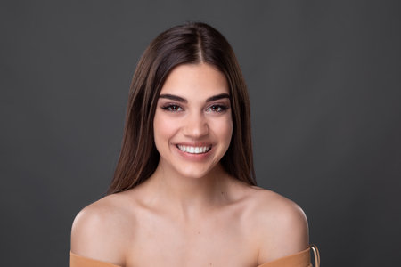 Beautiful young woman with clean perfect skin. Portrait of beauty model with natural nude make up and touching her face. Spa, skincare and wellness. Close up, copyspace.の写真素材