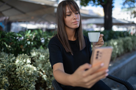 Morning in cafe - attractive woman in black drinking coffee and make selfie photo for social networks. stock photoの写真素材