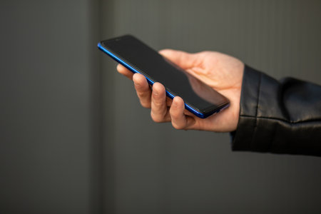 Closeup image of male hands with mobile phone, searching internet or social networks, blurred backgroundの写真素材