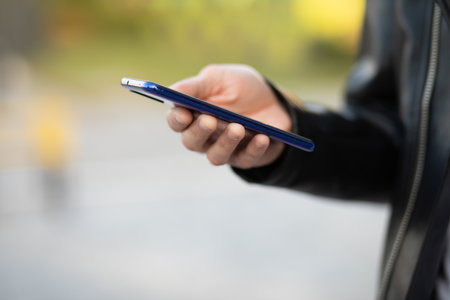 Closeup shot of an young modern man holding mobile smartphone in hand,  chatting via internet applicationの写真素材