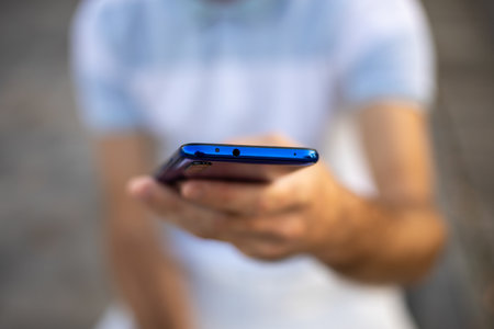 Closeup shot of an young modern man holding mobile smartphone in hand,  chatting via internet applicationの写真素材
