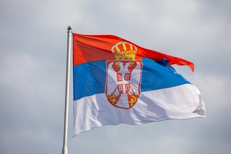 Serbian national flag on wind, outdoor, cloudy backgroundのeditorial素材