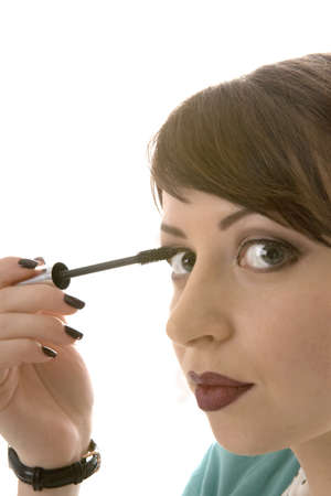 the beautiful young girl makes up eyelashes,  a portrait on a white backgroundの写真素材