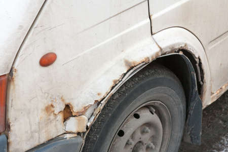 the rusted side panel of the old car with through holesの写真素材