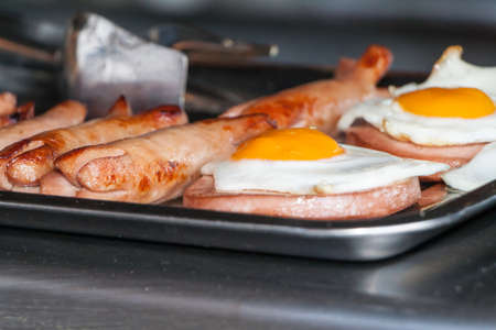 fried eggs and fried sausages on a counter in street cafe in summer dayの写真素材