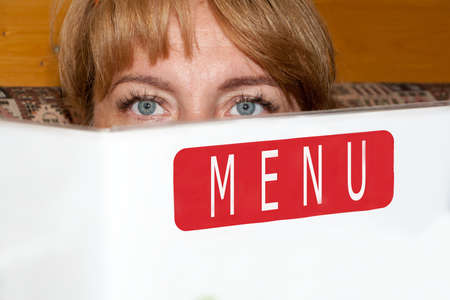 the beautiful girl holds the menu in hand, sitting in cafeの写真素材