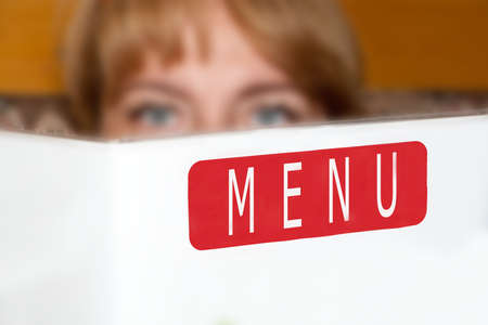 the beautiful girl holds the menu in hand, sitting in cafe