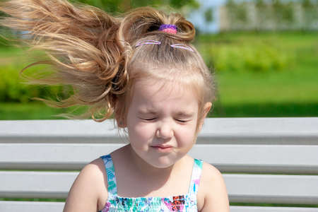 Portrait of the young girl with the hair fluttering from wind in summer day