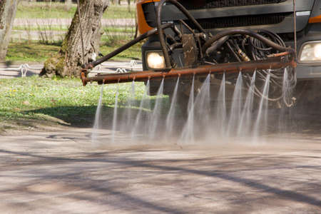 the water cart waters paths in the park in clear summer day