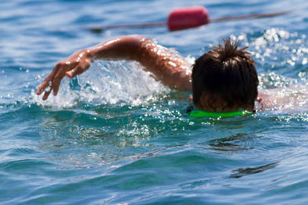 the teenager swims in a mask in the blue sea in clear summer dayの写真素材