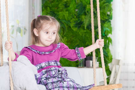 portrait of a three year old smiling little girl on a swing with a an elephantの写真素材