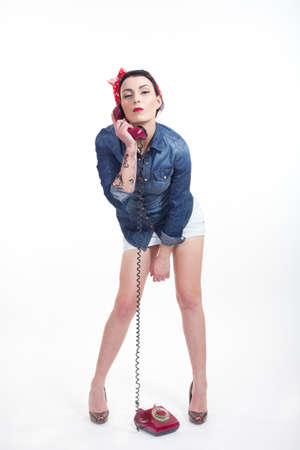 Woman with red kerchief and denim shirt talking on a phoneの写真素材