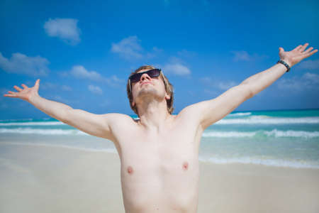 Young man standing near the sea with his arms stretchedの写真素材