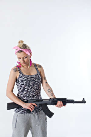 Dangerous young woman holding automatic rifleの写真素材
