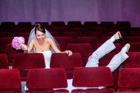 Young couple fooling around in the cinema theatre on their wedding dayの写真素材