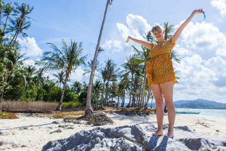 Young woman standing on a perfect palm beach in Philippinesの写真素材