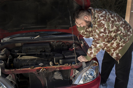 Mechanic wonders what went wrong in the car. Helpless man looks at the spoiled engine in the car.の写真素材
