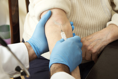 Hands doctor wearing gloves when Administering the injection to the patient.の写真素材
