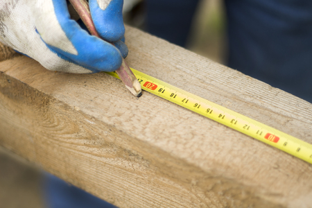 The hand of a construction worker points with a pencil on a wooden edge.の写真素材